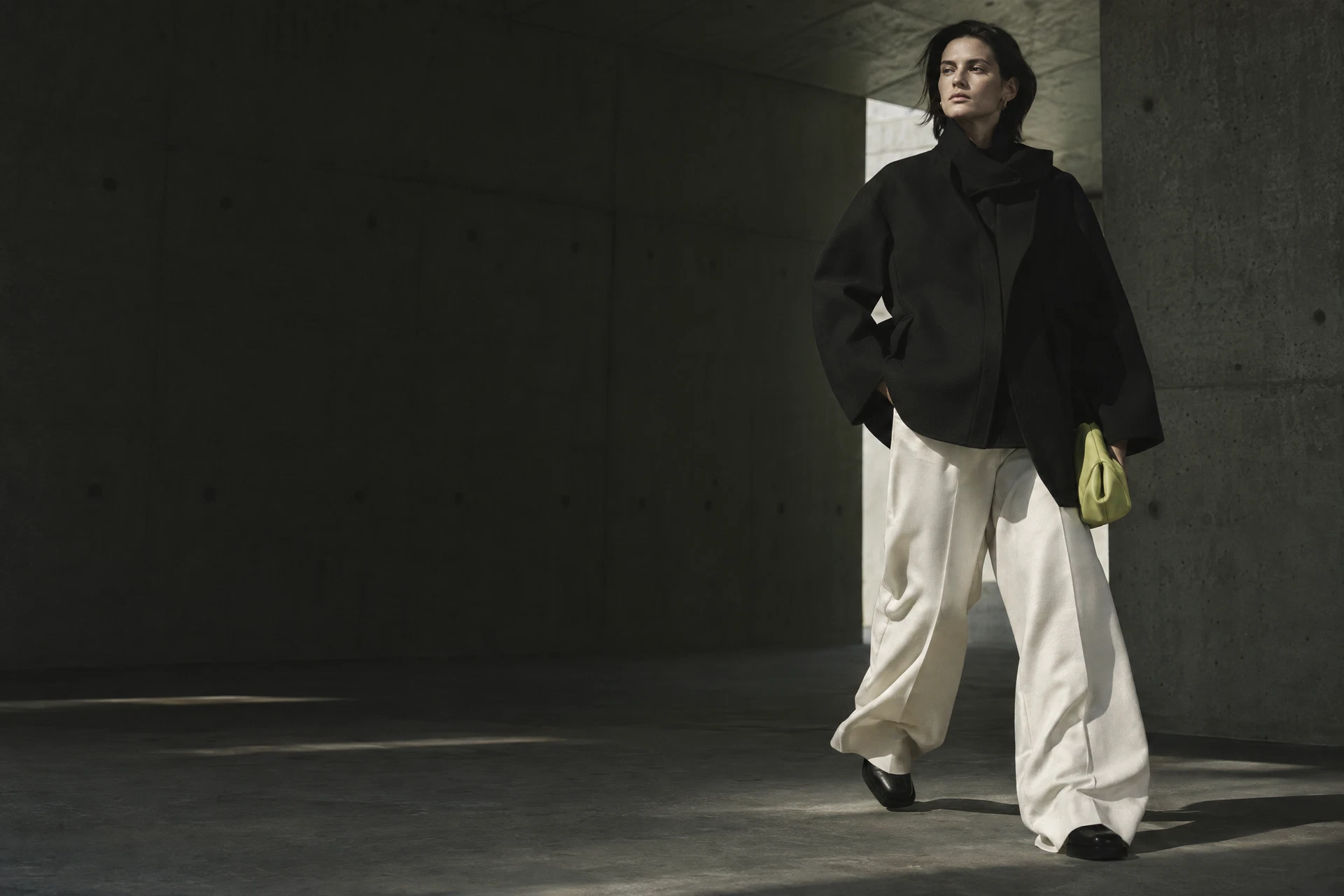 Silhouette portant une veste noire structurée et un pantalon écru